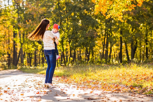 Mother and little daughter playing together in autumn park.