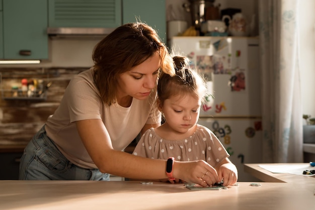 Mother and little daughter playing together in kitchen at home