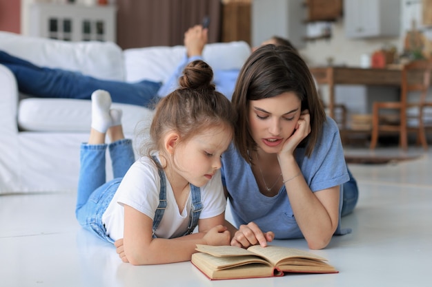 Madre e figlia hanno letto un libro insieme, sdraiate sul pavimento in soggiorno.