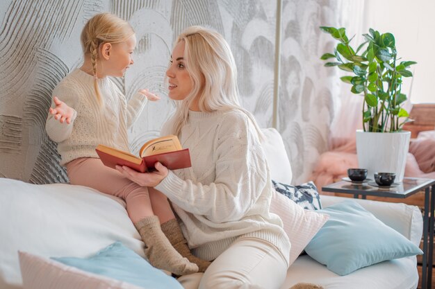 Mother and little daughter reading book