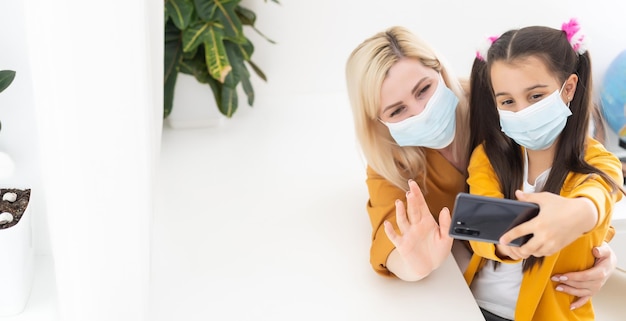 mother and little daughter take a selfie in masks.