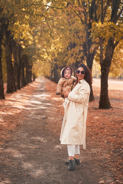 Madre e figlia piccola camminano nel parco d'autunno