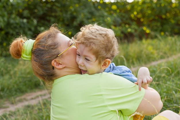 A mother and a little disabled boy hug and play in nature. Disability. Infantile paralysis. Mother's love. Happy childhood.