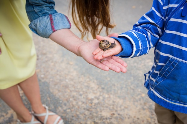 Mother and little eastern handsome baby boy playing outdoor with a snail