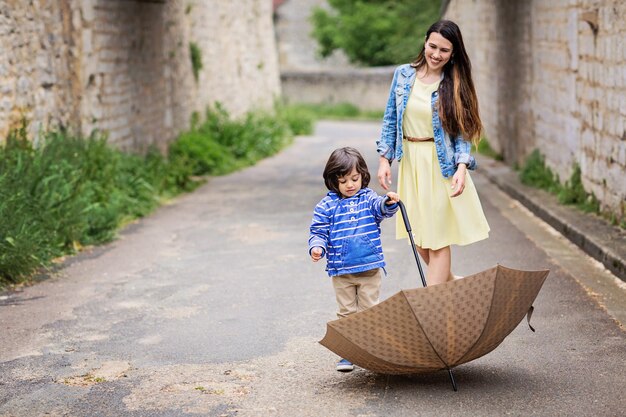 Mother and little eastern handsome baby boy playing with umbrella outdoor in old town