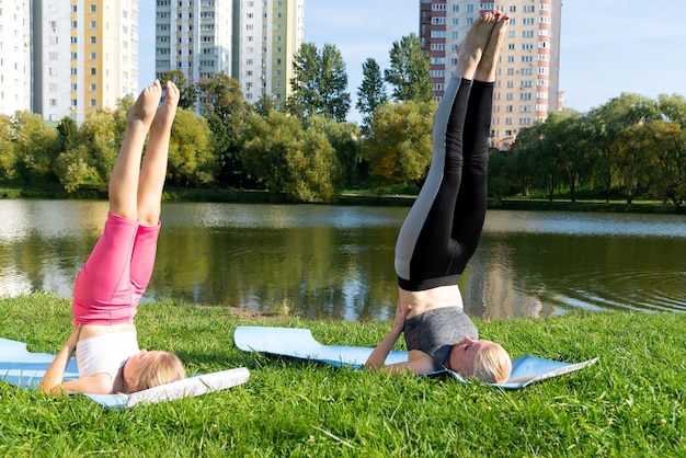 Mother and little girl doing yoga in the city park.