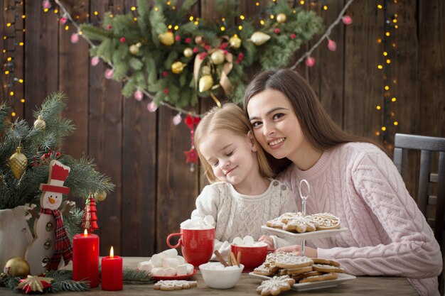 母と自宅のクリスマスクッキーを持つ少女