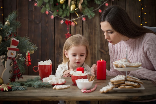 母と自宅のクリスマスクッキーを持つ少女