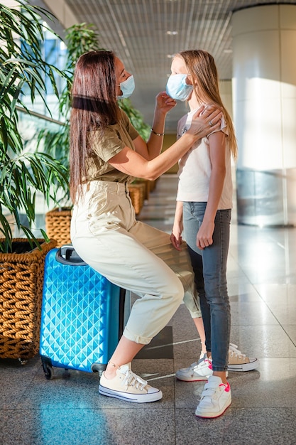 어머니와 공항에서 nedical 마스크와 어린 소녀. 코로나 바이러스에 대한 보호