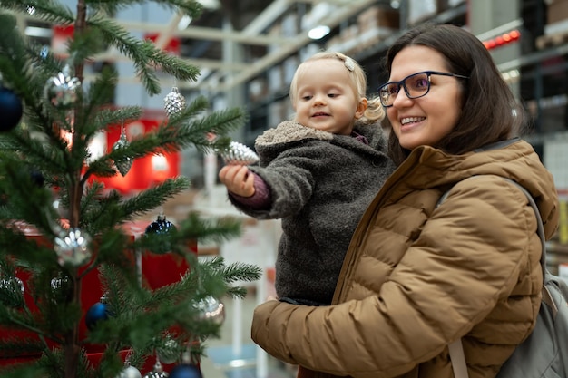 Mother and little toddler daughter choosing new year gifts in the store little girl playing with