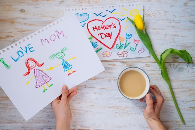 Foto madre guarda la foto del bambino con congratulazioni per la festa della madre mentre beve caffè vista dall'alto