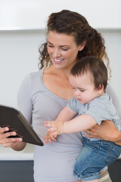 Foto madre guardando tablet digitale mentre trasportano il bambino