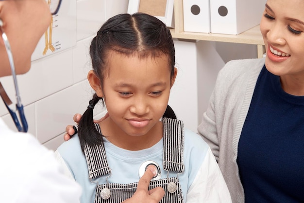 Foto madre che guarda il dottore che esamina la ragazza in clinica