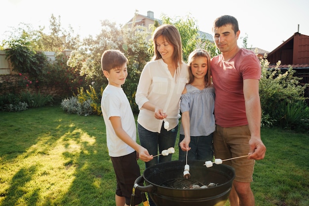 Foto generi l'esame di suo figlio mentre arrostiscono la caramella gommosa e molle sul barbecue al parco