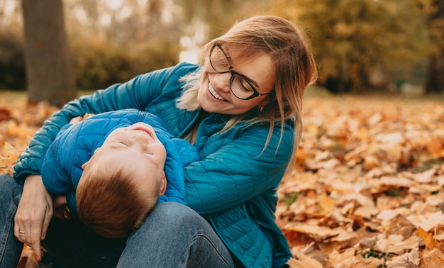 Madre guardando attraverso gli occhiali il suo piccolo figlio durante una passeggiata autunnale