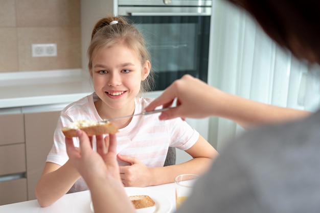 Mother making her daughter sandwich for breakfast