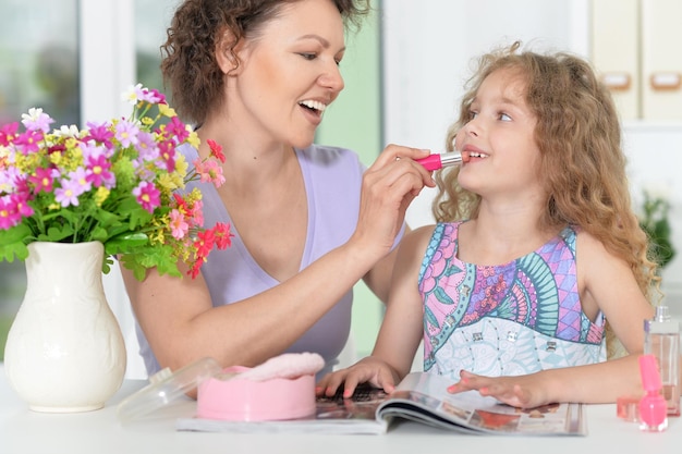 Mother making make up to her daughter, coloring lips