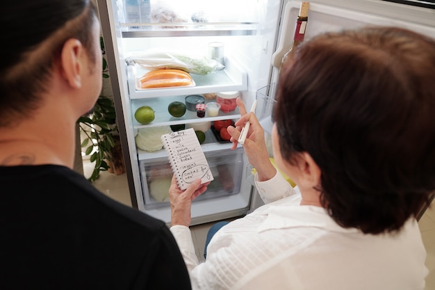 Mother making shopping list for her son