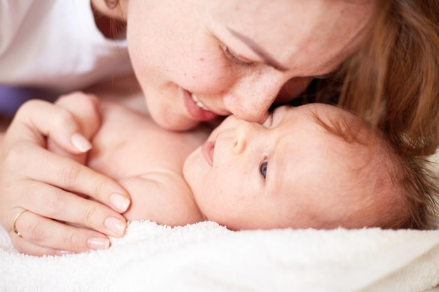 Photo mother massaging her newborn baby boy realistic home portrait