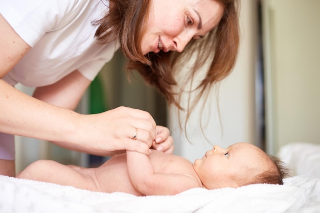 母は彼女の生まれたばかりの男の子をマッサージします 現実的な家の肖像画