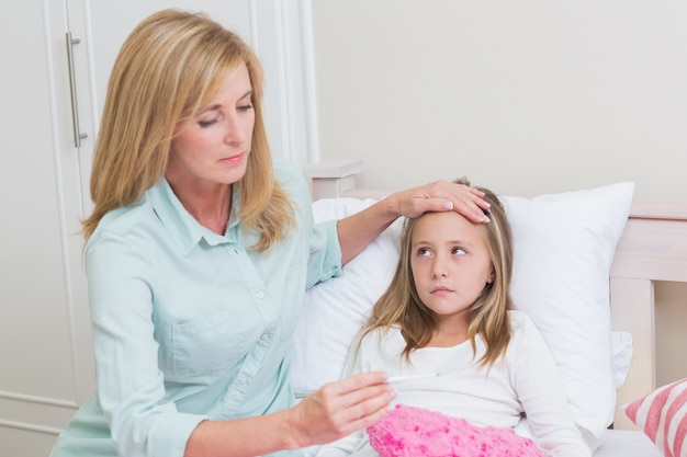 Mother measuring her daughters temperature