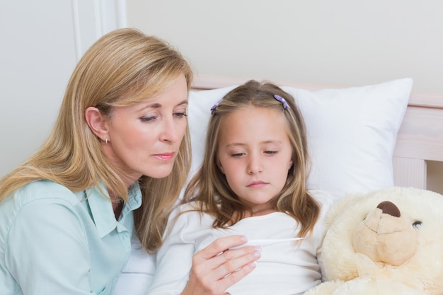 Photo mother measuring her daughters temperature