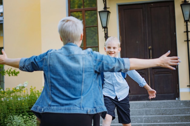 Mother meets children from school Caucasian boy and girl running towards mom hugging her