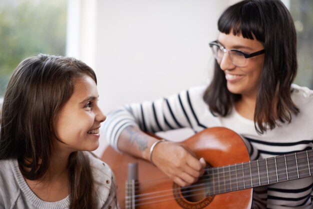 Foto madre musica e chitarra nel soggiorno per la figlia rilassarsi e godersi insieme sul divano legare donna e bambino con il sorriso sul divano intrattenimento e mamma suonare con uno strumento musicale