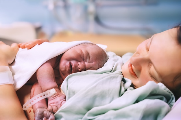 mother and newborn child birth in maternity hospital mom hugging her newborn baby after delivery