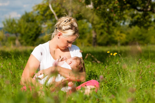 Foto madre che allatta bambino sul prato