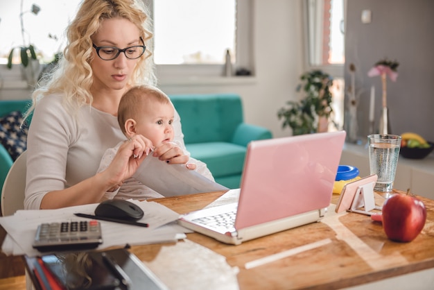 Mother opening envelope at home office