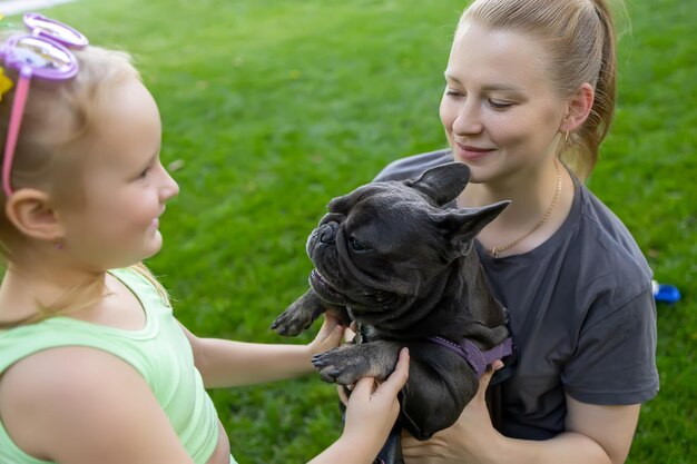 Mother passes the dog to her little daughter oni in the park