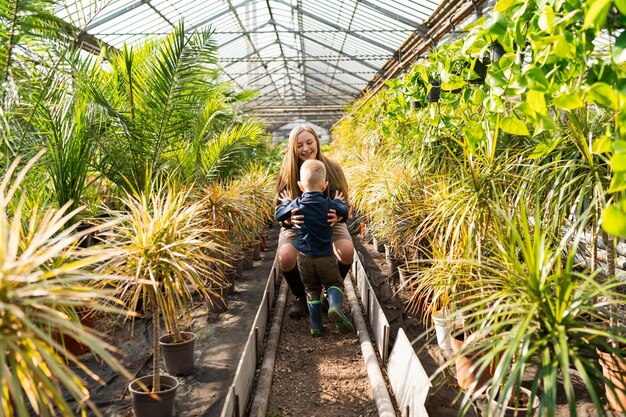 Mother picks up her son while walking in the greenhouse