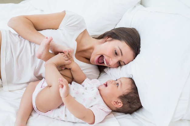 mother playing with daughter on bed 