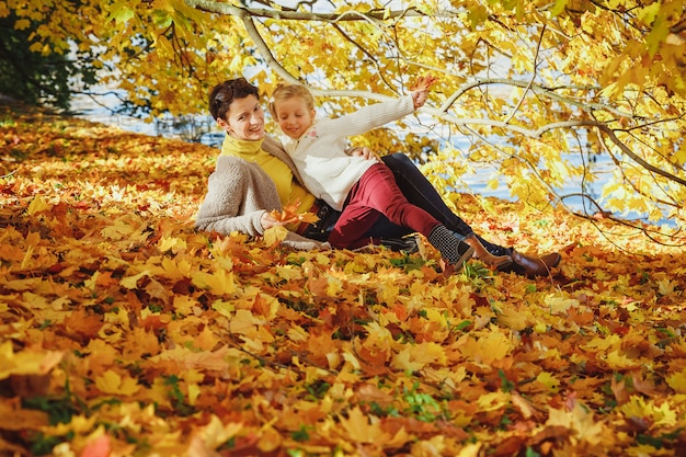 Mother playing with her daughter in autumn park. Mom and her child playing together outdoors. Happy loving family having fun. stylish mother and child wear. 