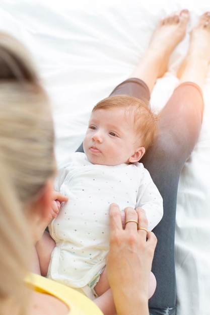 Photo mother playing with newborn girl on bed at home