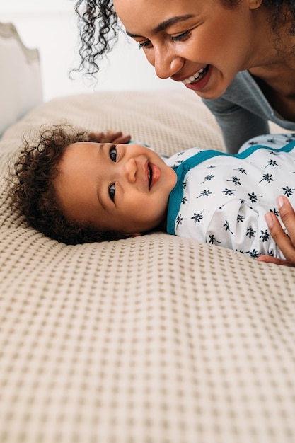 mother playing with son on bed at home