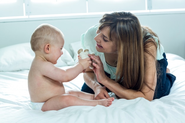 Mother playing with son on bed at home