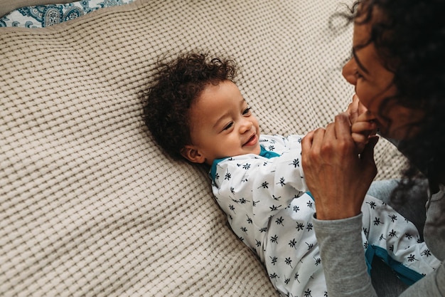 Photo mother playing with son on bed