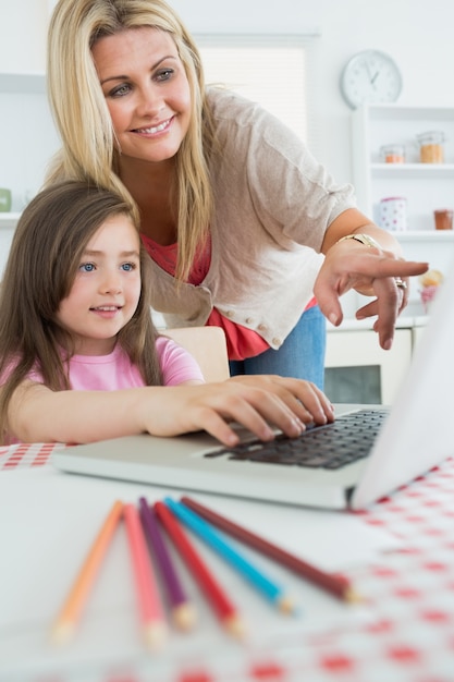 Mother pointing at laptop with daughter sitting down