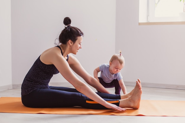 Photo mother practices yoga at home with her child