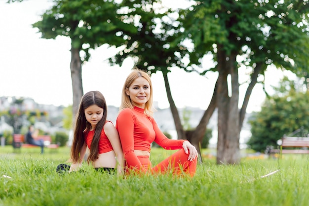 Mother practicing yoga with her daughter in the open air