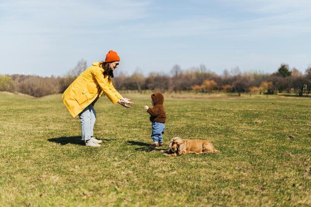 a mother pulls her hands to a child a spaniel dog sits next