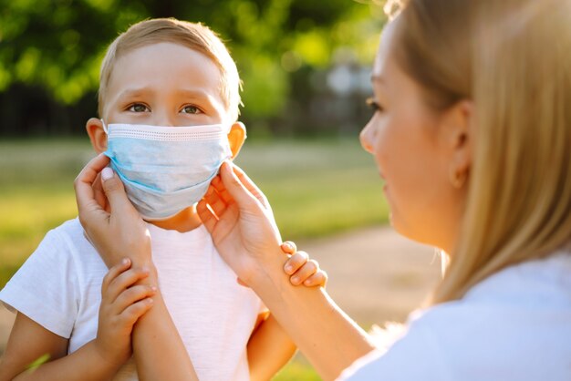 Mother puts on the child sterile medical mask in the park Covid2019