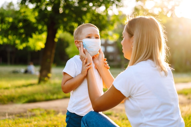 Mother puts on the child sterile medical mask in the park Covid2019