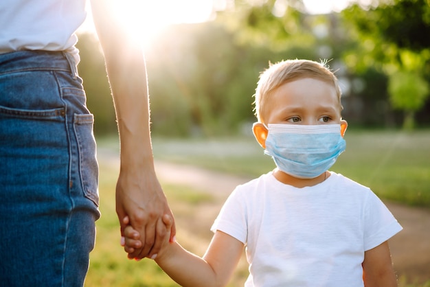 Mother puts on the child sterile medical mask in the park Covid2019