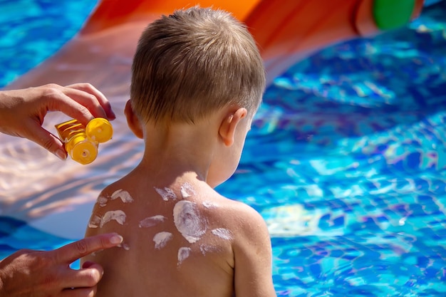 Mother puts cream on her son's back Caring for baby skin Sunscreens in the travel