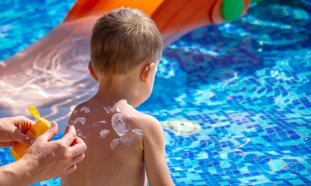 Mother puts cream on her son's back Caring for baby skin Sunscreens in the travel