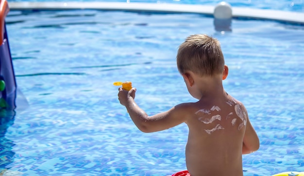 Mother puts cream on her son's back Caring for baby skin Sunscreens in the travel