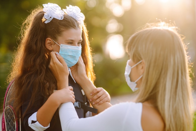 Mother puts on a protective sterile mask on a schoolgirl's. COVID-19 quarantine.